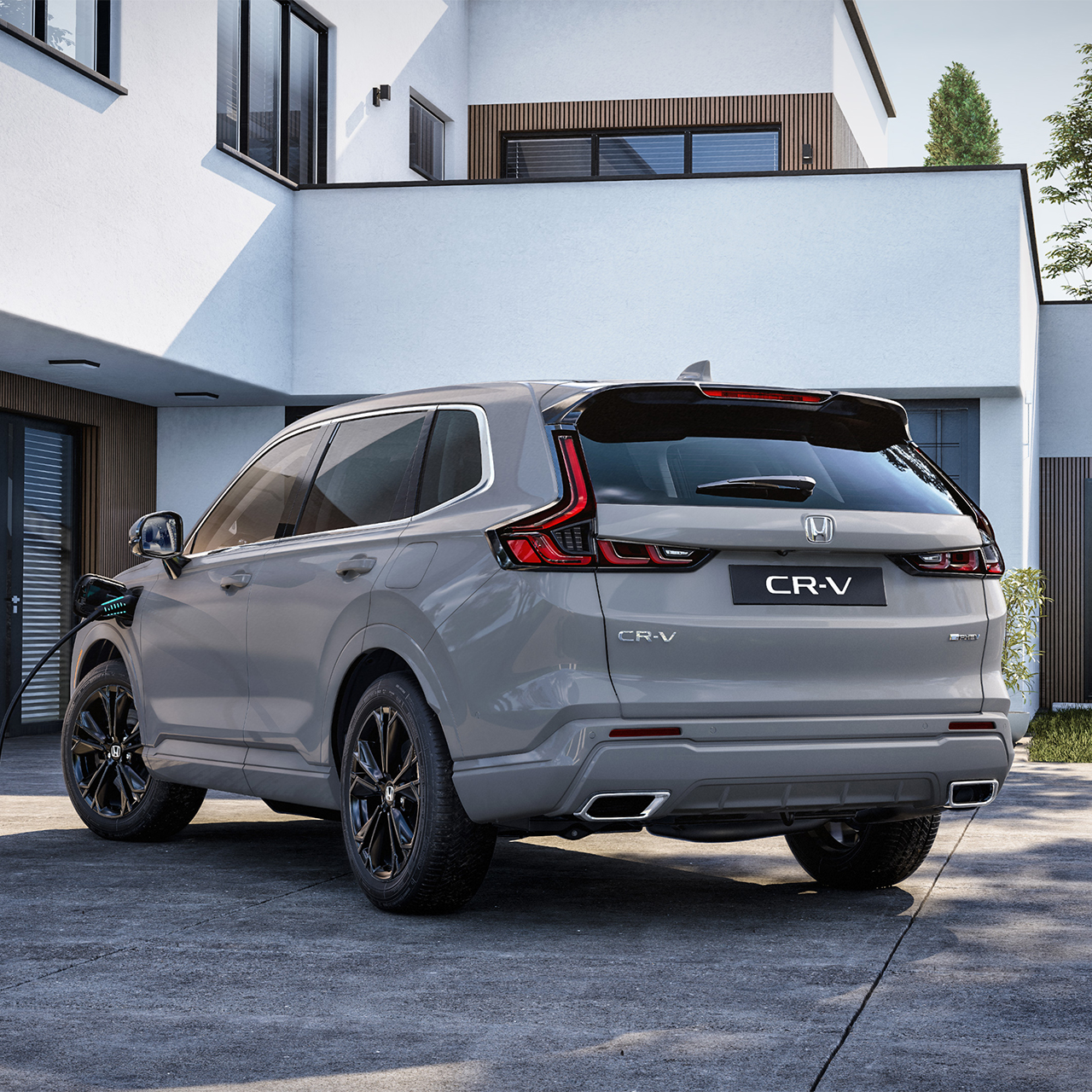 En Honda CR-V Plug-in Hybrid som er tilkoblet for lading, sett skrått bakfra.